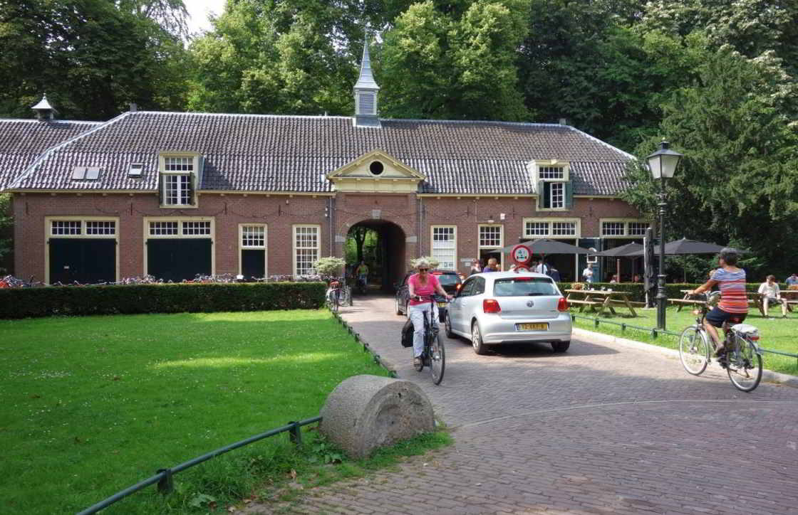 Het poortgebouw van Huis Rhijnauwen Fietsers fietsen onder het poortgebouw van Huis Rhijnauwen door