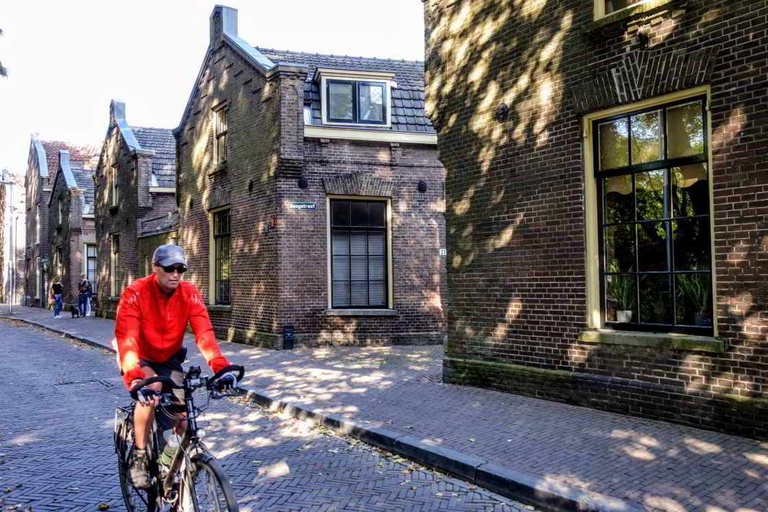 Fietsen langs de Zeven Steegjes Fietser in oranje jack voor de Zeven Steegjes